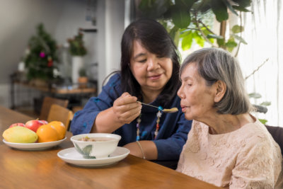female feeding elderly woman