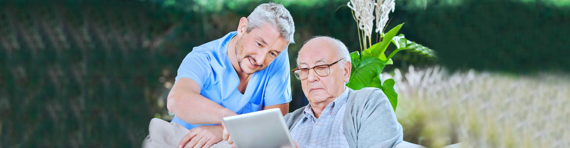 male assisting elderly man with tablet